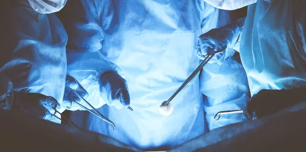 Grupo de cirurgiões usando máscaras de segurança realizando operação. Conceito de medicina — Fotografia de Stock