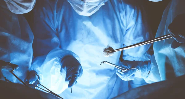 Sekelompok ahli bedah memakai masker pengaman untuk melakukan operasi. Konsep kedokteran — Stok Foto