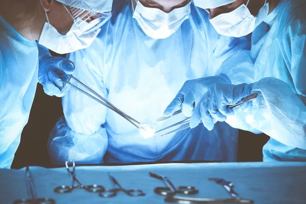 Grupo de cirurgiões usando máscaras de segurança realizando operação. Conceito de medicina — Fotografia de Stock