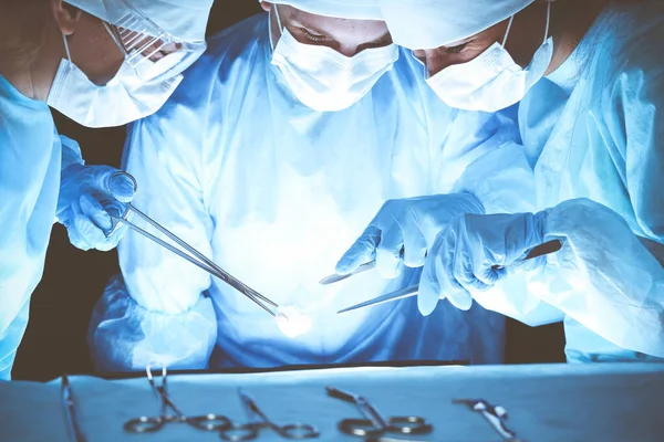 Grupo de cirurgiões usando máscaras de segurança realizando operação. Conceito de medicina — Fotografia de Stock