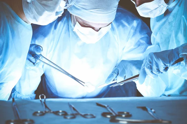 Группа хирургов в защитных масках, выполняющих операцию. Концепция медицины — стоковое фото
