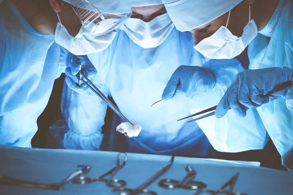 Grupo de cirurgiões usando máscaras de segurança realizando operação. Conceito de medicina — Fotografia de Stock