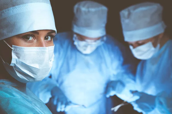 Group of surgeons wearing safety masks performing operation. Medicine concept — Stock Photo, Image