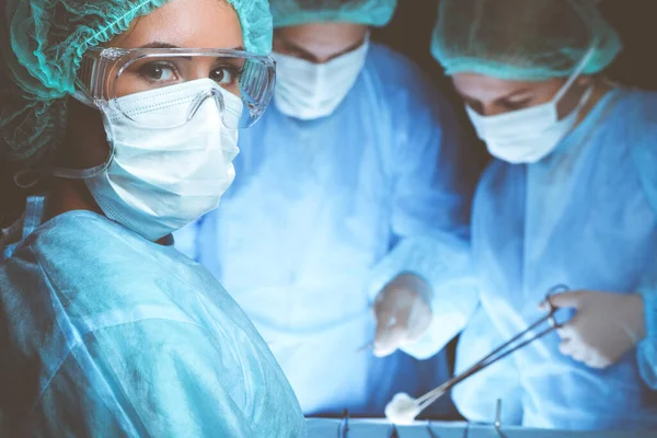 Grupo de cirujanos con máscaras de seguridad realizando la operación. Concepto de medicina — Foto de Stock