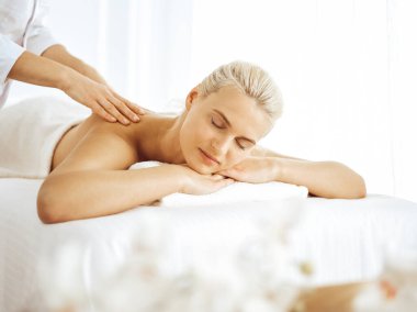 Güzel sarışın kadın kapalı gözlerle sırt masajından hoşlanıyor. Spa salonu konsepti