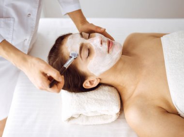 Güzel esmer kadın kapalı gözlerle kozmetik maske takmaktan zevk alıyor. Tıp ve kaplıca merkezi kavramlarında rahatlatıcı tedavi