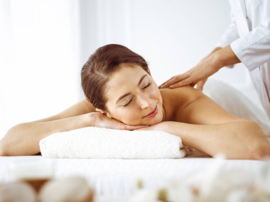 Güzel esmer kadın gözleri kapalı sırt masajından hoşlanıyor. Spa ve tıp konsepti