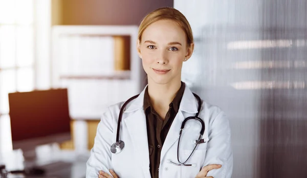 Allegro sorridente medico donna in piedi con le braccia incrociate in clinica. Ritratto di donna medico amichevole. Concetto di medicina — Foto Stock