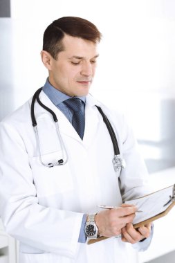 Doktor, ilaç kayıtlarını doldurmak için pano kullanıyor. Klinikte mükemmel bir tıbbi hizmet. Hastanede çalışan bir doktor. Tıp ve sağlık hizmetleri kavramları