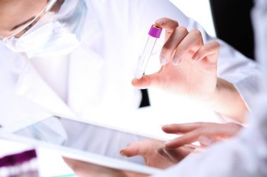 Koronavirüs salgını. Koruyucu gözlüklü profesyonel kadın bilim adamı laboratuarda reaktörlerle araştırma tüpü kullanıyor. İlaç ve virüs koruması kavramları