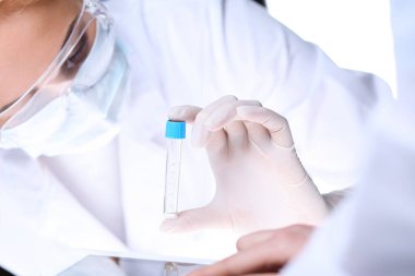 Koronavirüs salgını. Koruyucu gözlüklü profesyonel kadın bilim adamı laboratuarda reaktörlerle araştırma tüpü kullanıyor. İlaç ve virüs koruması kavramları