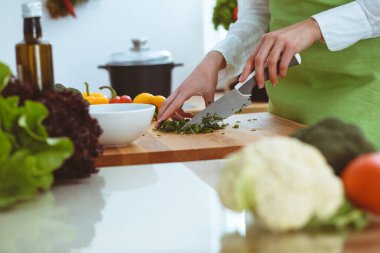Mutfakta pişen bilinmeyen insan elleri. Kadın sebze salatasıyla meşgul. Sağlıklı yemek ve vejetaryen gıda konsepti.