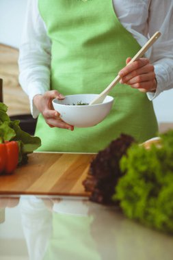 Mutfakta pişen bilinmeyen insan elleri. Kadın sebze salatasıyla meşgul. Sağlıklı yemek ve vejetaryen gıda konsepti.