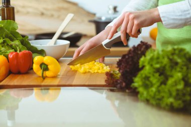 Mutfakta pişen bilinmeyen insan elleri. Sarı dolma biber dilimleyen kadın. Sağlıklı yemek ve vejetaryen gıda konsepti.