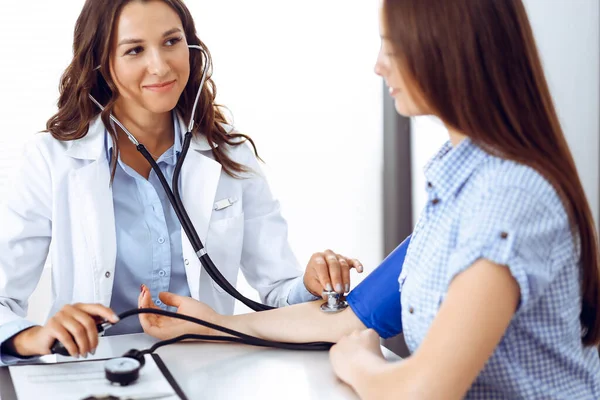 Docteur avec un stéthoscope à la main examinant sa patiente. Soins de santé, cardiologie et médecine concepts — Photo