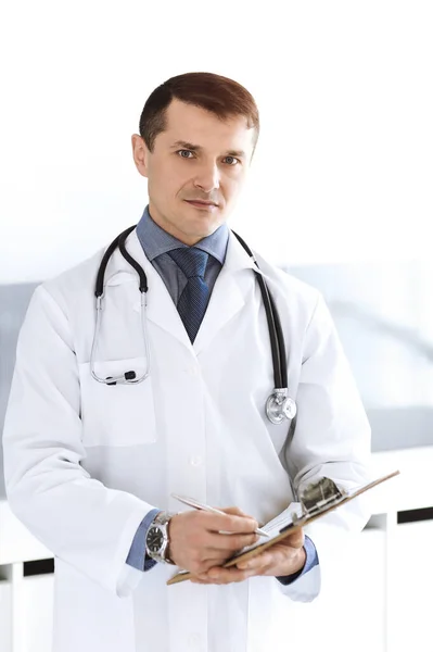 Doctor hombre usando portapapeles para llenar los registros del historial de medicamentos. Servicio médico perfecto en la clínica. Médico trabajando en el hospital. Medicina y conceptos sanitarios —  Fotos de Stock