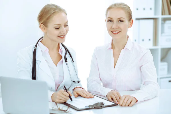 Médico y paciente hablando en el consultorio del hospital mientras están sentados en el escritorio. Atención médica y atención al cliente en medicina — Foto de Stock