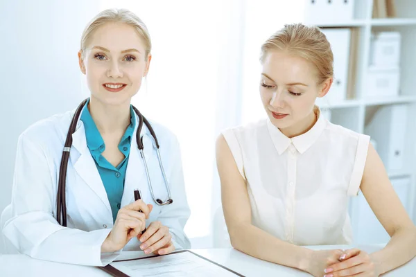 Dottore e paziente che parlano nello studio dell'ospedale mentre sono seduti alla scrivania. Assistenza sanitaria e servizio clienti in medicina — Foto Stock