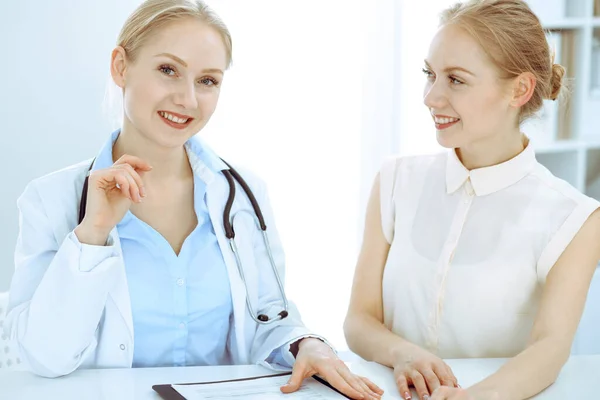 Médico y paciente hablando en el consultorio del hospital mientras están sentados en el escritorio. Atención médica y atención al cliente en medicina — Foto de Stock