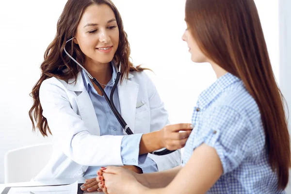 Doctor with a stethoscope in the hand examining her female patient. Health care, cardiology and medicine concepts Royalty Free Stock Photos