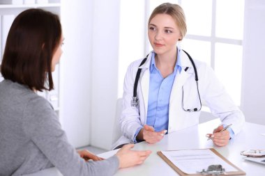 Hastane muayenehanesindeki genç kadın doktor ve hasta. Terapistin mavi renkli bluzu iyi görünüyor. Tıp ve sağlık hizmetleri kavramı