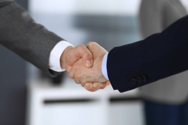 İş adamları toplantıdan ya da pazarlıktan sonra iş arkadaşlarıyla el sıkışıyorlar. Yakın plan. Modern ofisteki bir grup tanınmamış iş adamı ve kadın. Takım çalışması, ortaklık ve tokalaşma