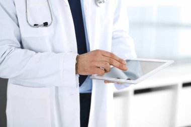Doktor, ağ araştırması ya da sanal hastalık tedavisi için tablet bilgisayar kullanıyor. Eller yakın çekim. Klinikte mükemmel bir tıbbi hizmet. Modern tıp, tıbbi veri ve sağlık hizmetleri kavramları. Ayarlanmış