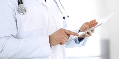 Doktor, ağ araştırması ya da sanal hastalık tedavisi için tablet bilgisayar kullanıyor. Eller yakın çekim. Klinikte mükemmel bir tıbbi hizmet. Modern tıp, tıbbi veri ve sağlık hizmetleri kavramları. Ayarlanmış