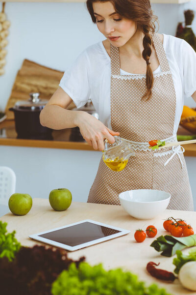 Молодая брюнетка готовит на кухне. Домохозяйка держит в руке деревянную ложку. Концепция питания и здоровья