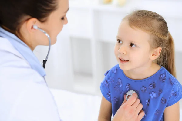 Dokter die een klein meisje onderzoekt met stethoscoop. Gelukkige glimlachende kindpatiënt bij gebruikelijke medische inspectie. Begrippen geneeskunde en gezondheidszorg — Stockfoto