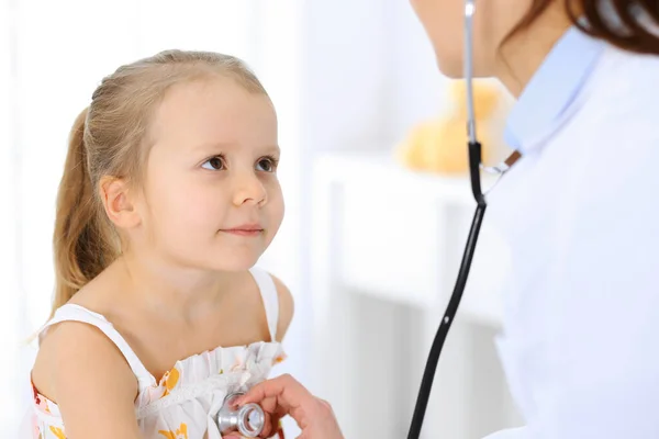 Doktor steteskopla küçük bir kızı muayene ediyor. Her zamanki tıbbi muayenede gülümseyen çocuk hasta. Tıp ve sağlık hizmetleri kavramları — Stok fotoğraf