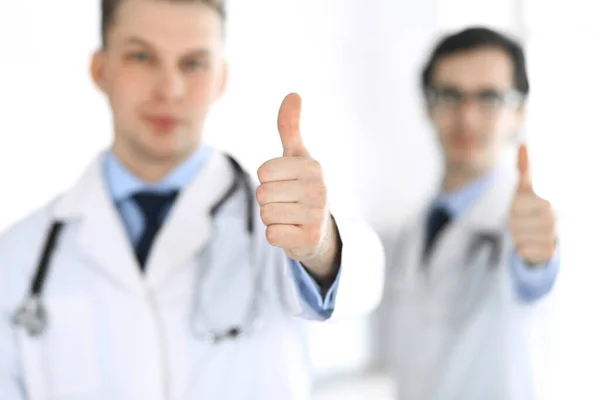 Az orvos egyenesen áll a kollégájával, és mutogatja a hüvelykujját. Orvosok csoportja. Tökéletes orvosi ellátás a klinikán. Orvosi és egészségügyi koncepciók. Fényképezés — Stock Fotó