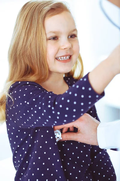 Médico examinando a un niño paciente por estetoscopio. Linda niña en la cita con el médico. Concepto de medicina. Foto tonificada —  Fotos de Stock