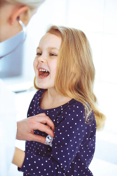 Médico examinando a un niño paciente por estetoscopio. Linda niña en la cita con el médico. Concepto de medicina. Foto tonificada —  Fotos de Stock