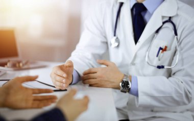 Bir doktor, hastanedeki güneşli dolapta birlikte otururken hastasıyla konuşuyor. Doktor ilaç kayıtlarını doldurmak için pano kullanıyor. Mükemmel tıbbi servis.