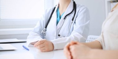 Doktor ve hasta hastanede masa başında otururken bir şey tartışıyorlar, yakın plan. İlaç ve sağlık hizmetleri