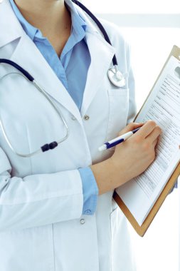Kadın doktor, panoya yakın çekim yaparken tıbbi form kullanıyor. Hastane ya da klinikte çalışan bir hekim. Sağlık, sigorta ve tıp konsepti