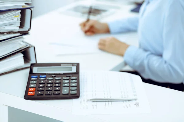 Calculator and binders with papers are waiting to be processed by business woman or bookkeeper back in blur. Internal Audit and tax concept — Stock Photo, Image