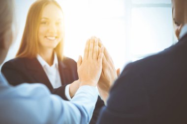 İş adamları takım çalışmasını göstermekten ve güneşli ofiste birlik ve ortaklık göstermekten mutlu olurlar. Başarı ve dostluk kavramları