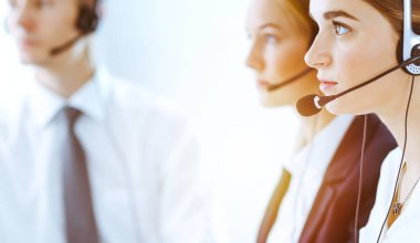 Güneşli ofiste çalışan bir grup farklı telefon operatörü. Kulaklıklı yakışıklı iş kadını müşterilere danışıyor. Çağrı merkezi ve iş adamları kavramı