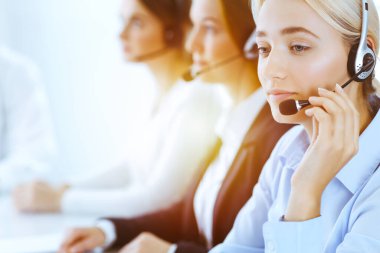 Güneşli ofiste çalışan bir grup farklı telefon operatörü. Kulaklıklı yakışıklı iş kadını müşterilere danışıyor. Çağrı merkezi ve iş adamları kavramı