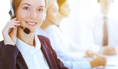 Güneşli ofiste çalışan bir grup farklı telefon operatörü. Kulaklıklı yakışıklı iş kadını müşterilere danışıyor. Çağrı merkezi ve iş adamları kavramı