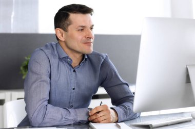 Modern ofiste bilgisayarla çalışan bir iş adamı. İş yerindeki erkek girişimcinin ya da şirket müdürünün vesikalığı. İş konsepti