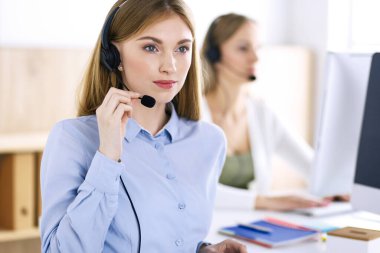 Çağrı merkezi operatörünün portresi. Kulaklık takmış bir grup insan müşterilere yardım etmeye hazır. İş konsepti