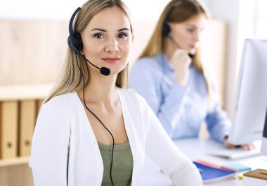 Çağrı merkezi operatörünün portresi. Kulaklık takmış bir grup insan müşterilere yardım etmeye hazır. İş konsepti