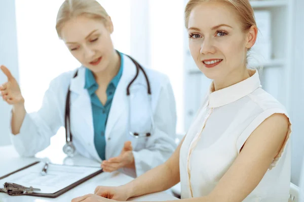 Médico y paciente hablando en el consultorio del hospital mientras están sentados en el escritorio. Atención médica y atención al cliente en medicina — Foto de Stock