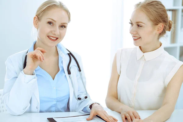 Médico y paciente hablando en el consultorio del hospital mientras están sentados en el escritorio. Atención médica y atención al cliente en medicina — Foto de Stock