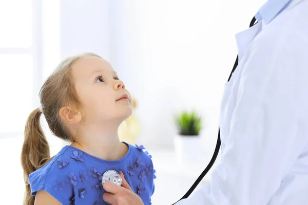 Arzt untersucht ein kleines Mädchen per Stethoskop. Glücklich lächelnder Kinderpatient bei der üblichen ärztlichen Untersuchung. Medizin- und Gesundheitskonzepte — Stockfoto