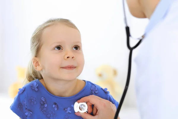 Γιατρός εξετάζει ένα κοριτσάκι με στηθοσκόπιο. Χαρούμενος χαμογελαστός ασθενής στη συνηθισμένη ιατρική εξέταση. Έννοιες ιατρικής και υγειονομικής περίθαλψης — Φωτογραφία Αρχείου