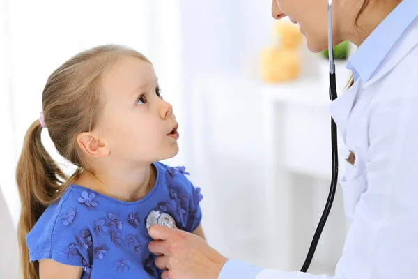Doutor examinando uma menina por estetoscópio. Paciente de criança sorridente feliz em inspeção médica habitual. Conceitos de medicina e saúde — Fotografia de Stock